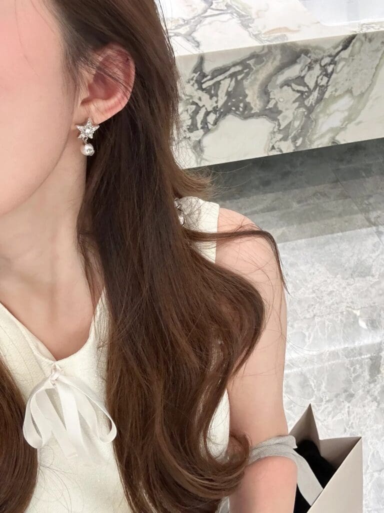 Chinese Influencer wearing jimmy choo earrings, marble background