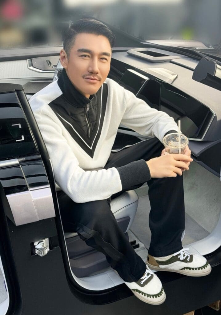 Chinese celebrity actor and model Hu Bing sitting in his car smiling, wearing mou shoes
