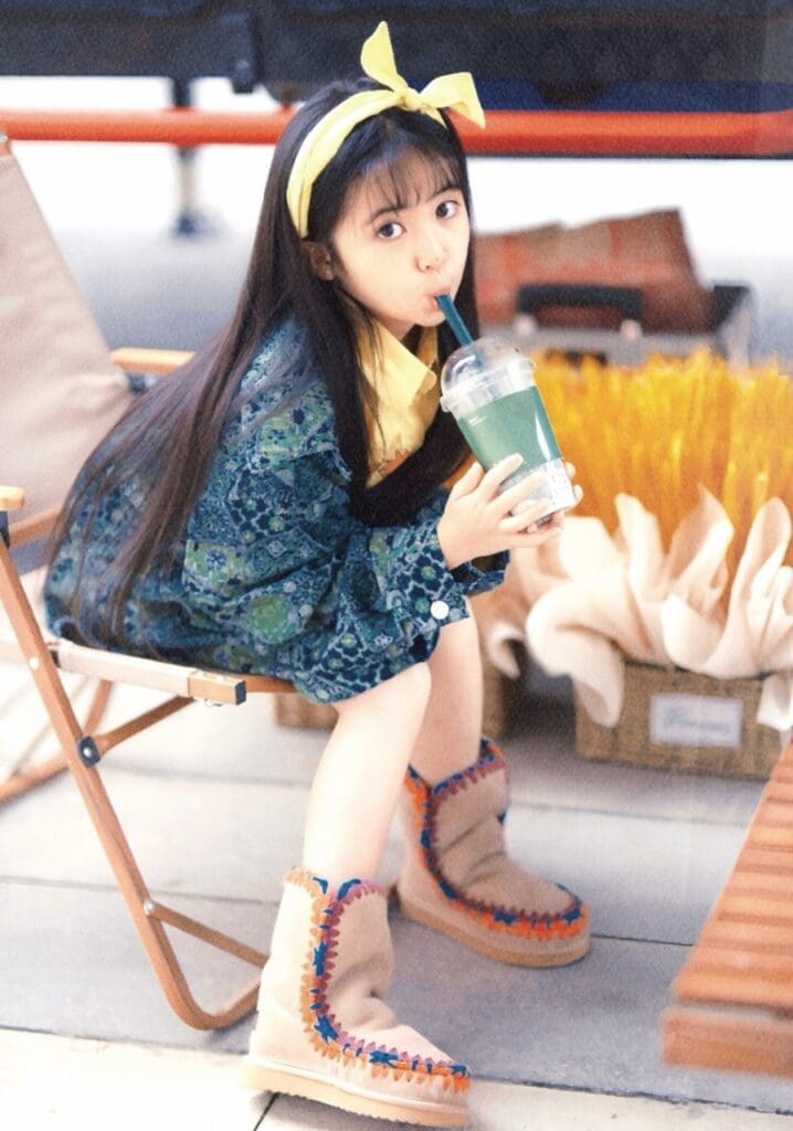 Chinese child celebrity actress Li Zhimo sitting on a chair sipping on bubble tea while wearing mou shoes